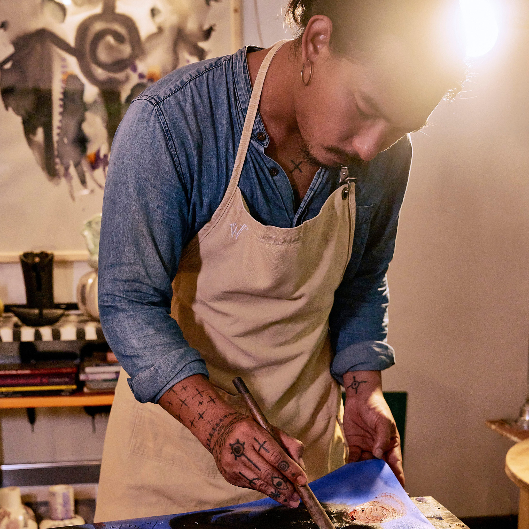 Eakarin in his art studio, he is wearing the Wiseguy Original Apron in the color Beige and is painting